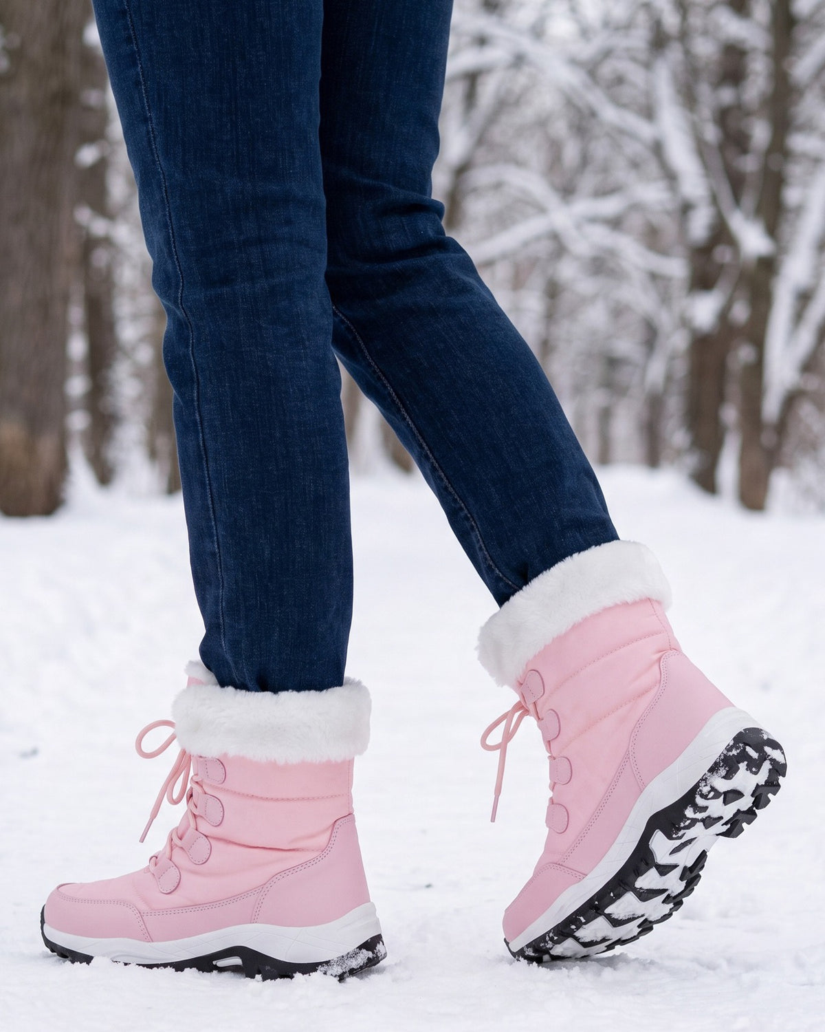 Birdie pink snow boots worn with jeans on a snowy park path