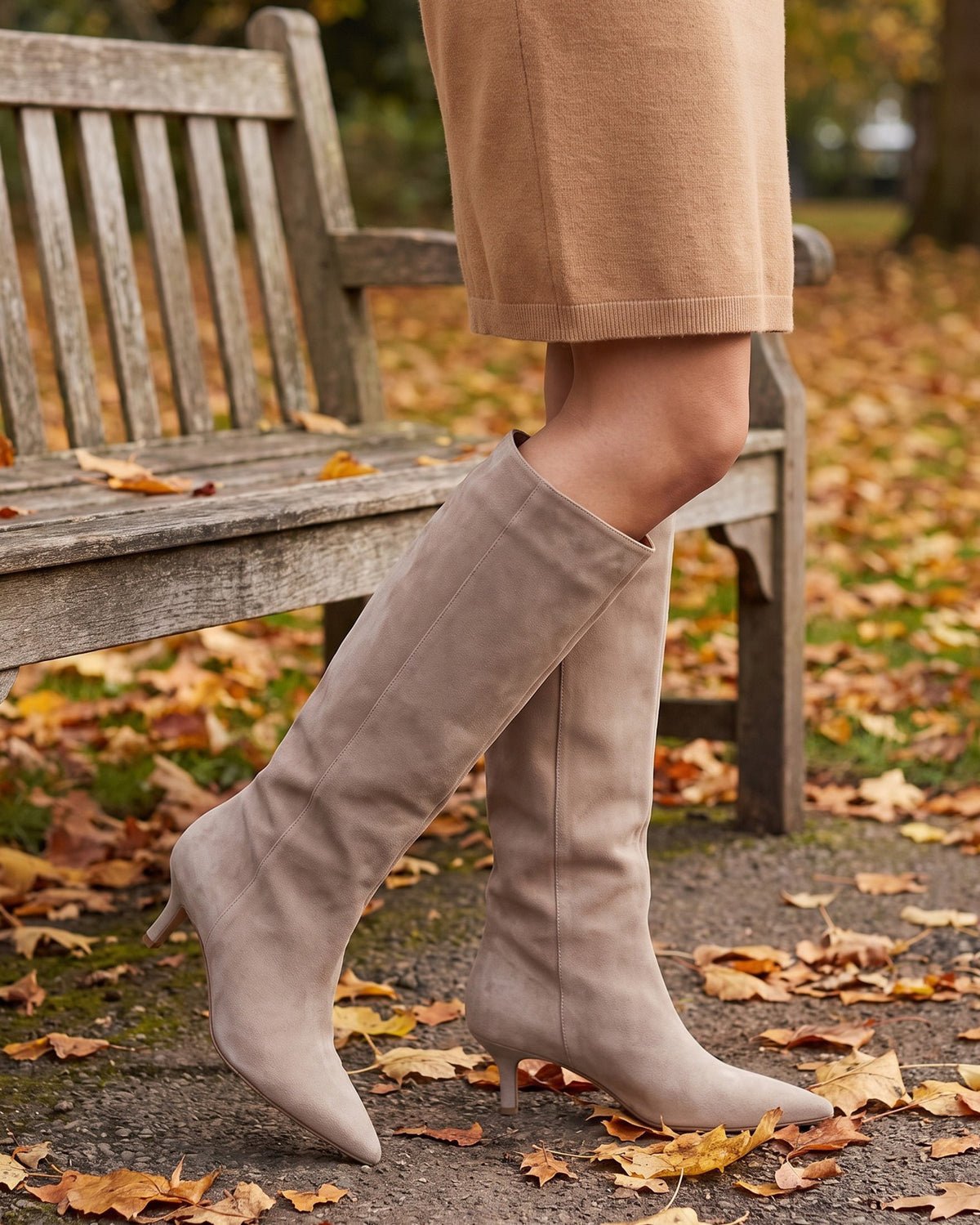 Sybil beige knee-high boots worn with a camel skirt by a park bench in autumn