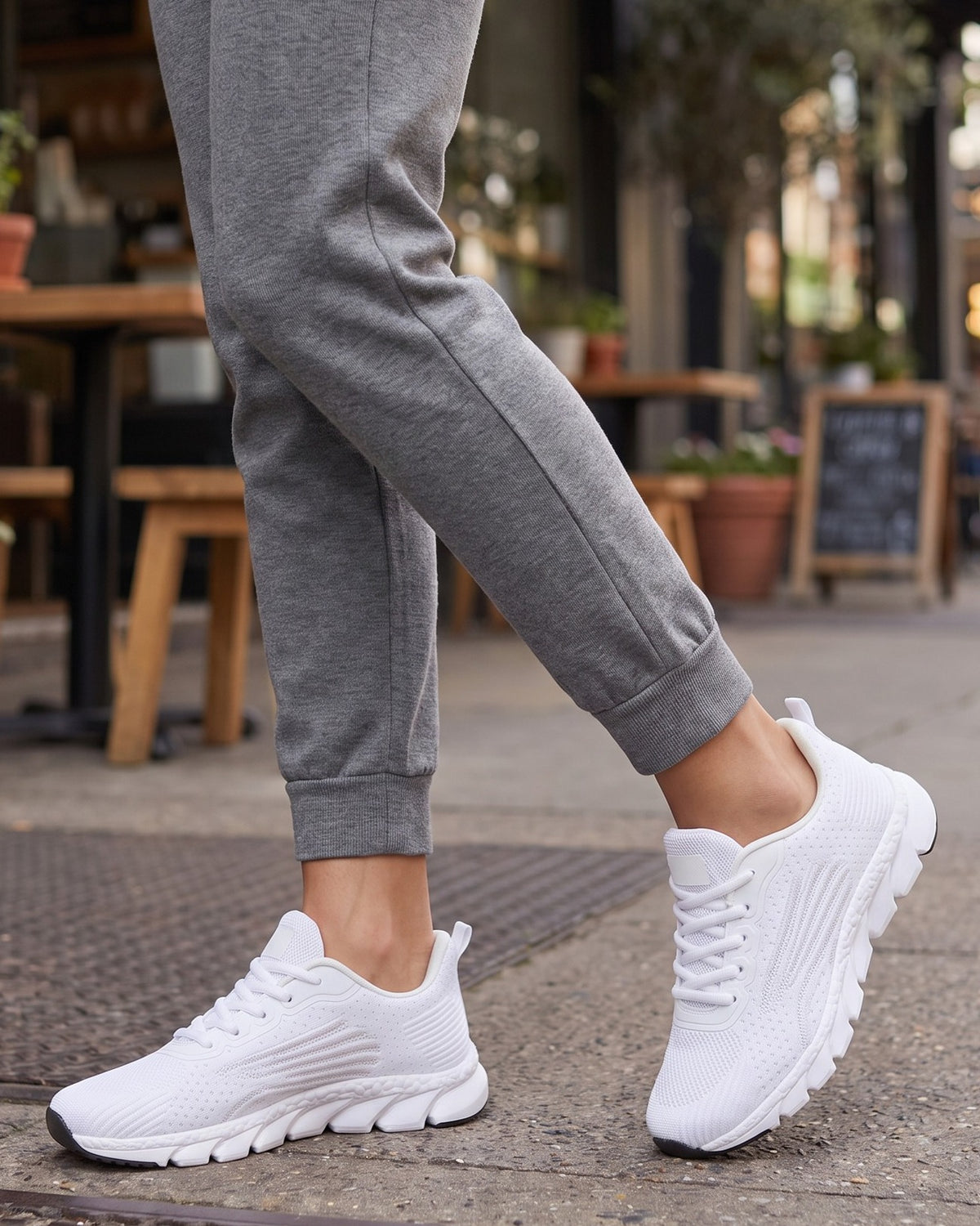 Wren white knit sneakers worn with grey joggers outside a café