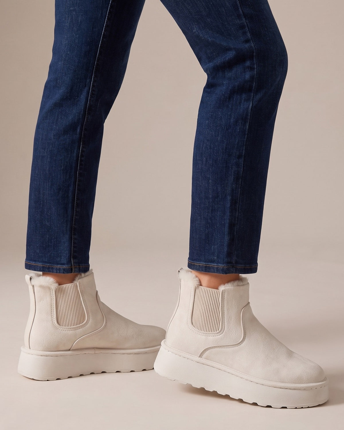 Coral cream snow boots worn with jeans, studio shot of legs