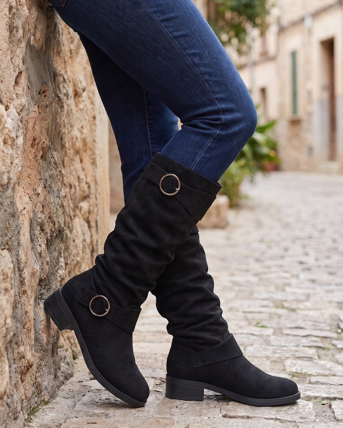 Esme slouch boots worn with jeans on a cobblestone lane