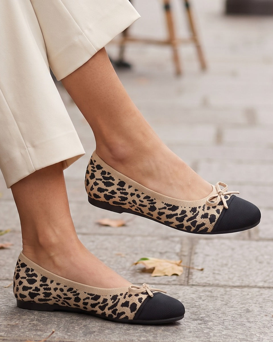 Isla leopard knit flats worn with cream trousers at a sidewalk café