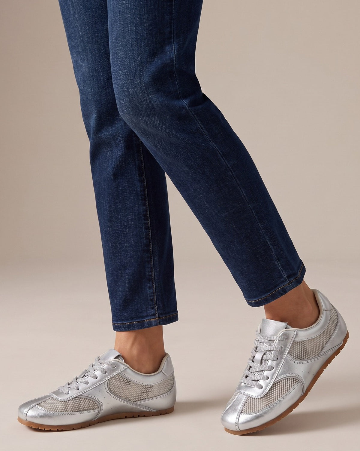 Juno silver sneakers worn with jeans, studio shot of legs
