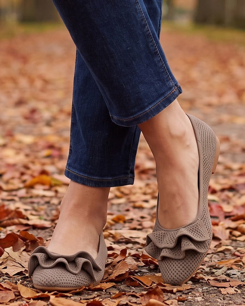 Mabel ruffle knit flats worn with jeans on a leaf-covered park path
