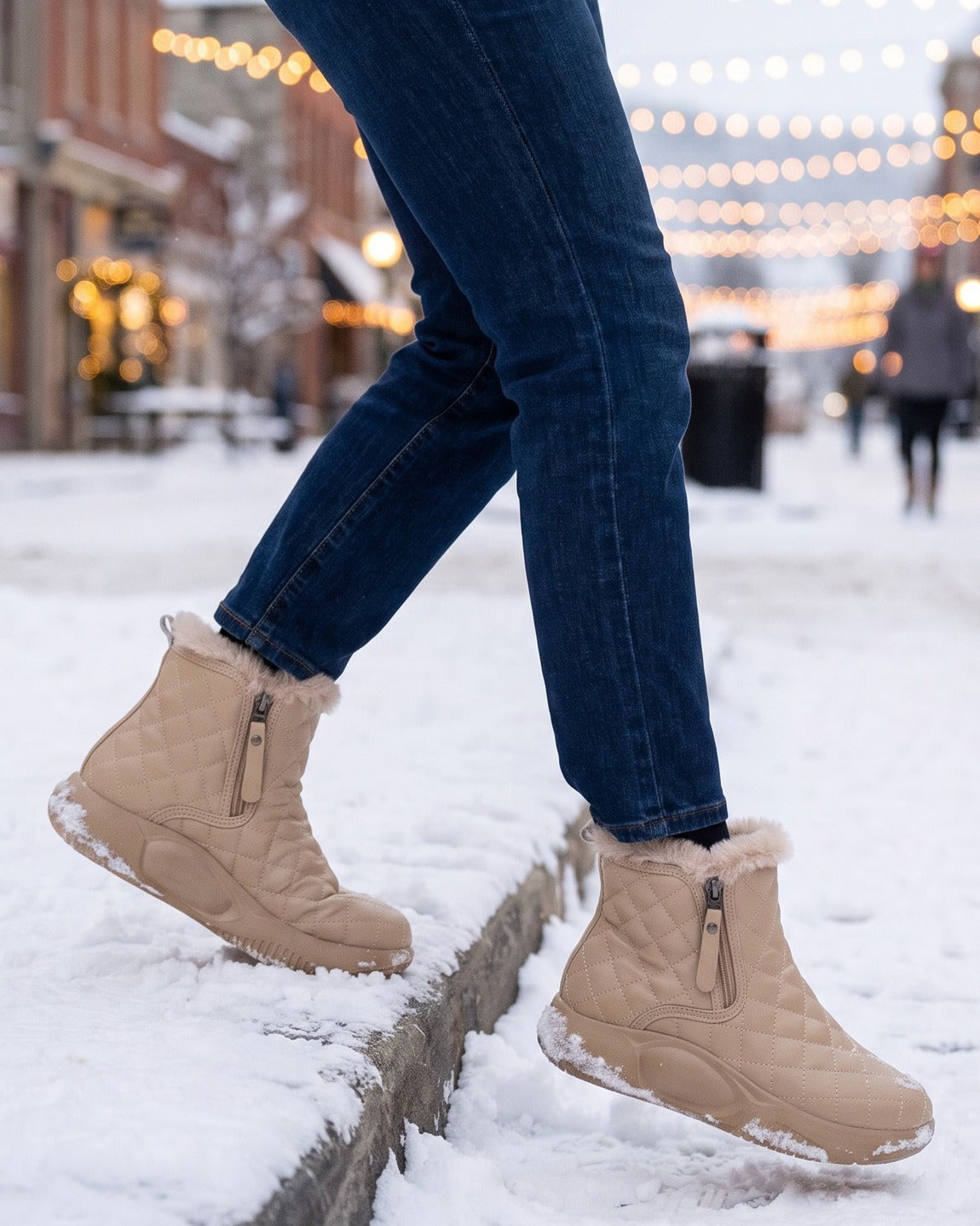 Maisie quilted boots worn with jeans on a snowy street with string lights