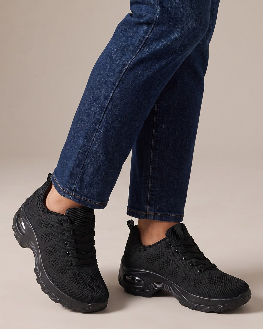 Nell black sneakers worn with jeans, studio shot of legs
