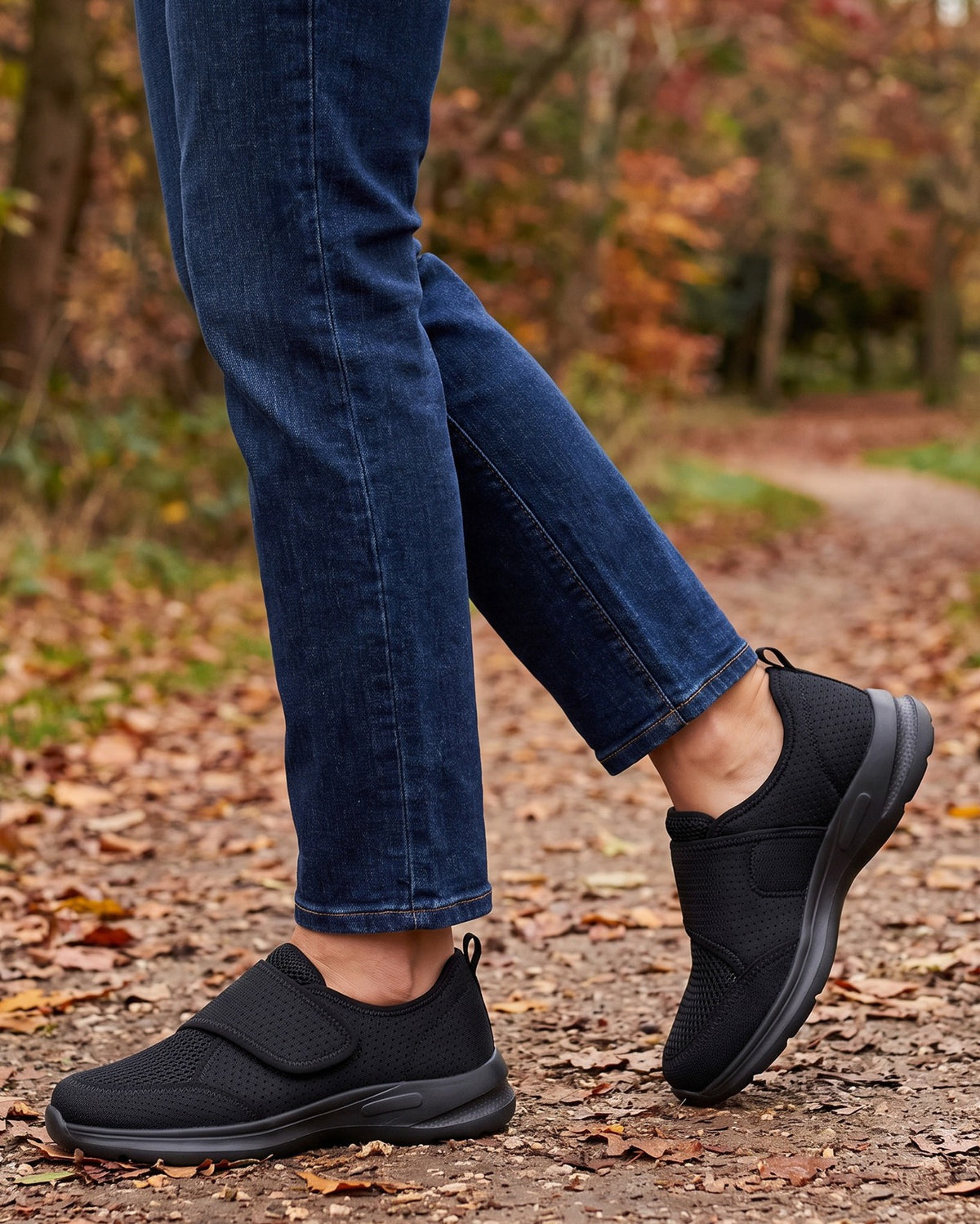 Opal black strap shoes worn with jeans on a leaf-covered park path