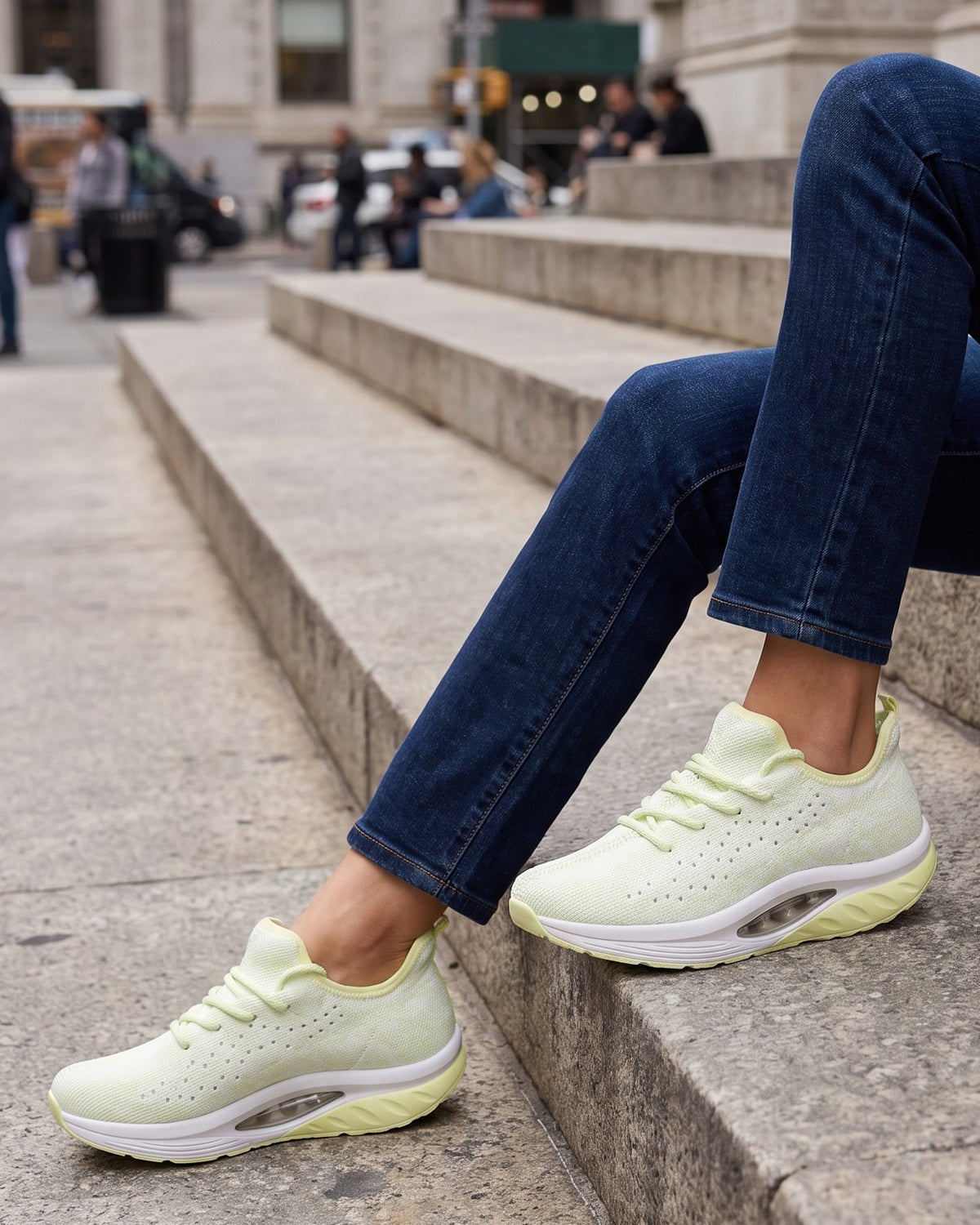 Pippa knit trainers worn with jeans, seated on stone city steps