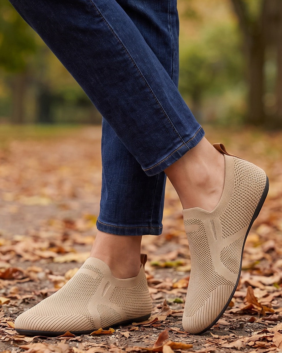 Reese tan knit loafers worn with jeans on a leaf-covered park path
