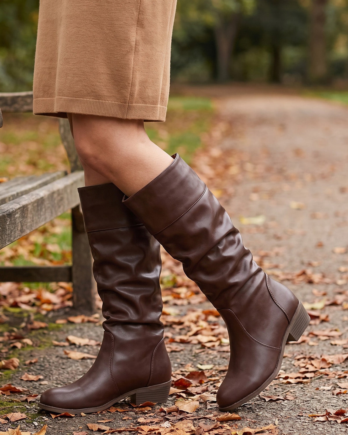 Stella brown riding boots worn with a camel skirt on an autumn park path