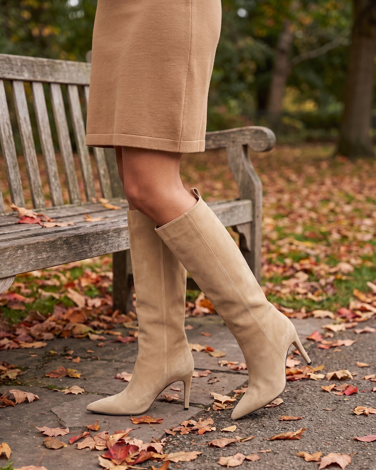 Vera beige knee-high boots worn with a camel skirt by a park bench in autumn