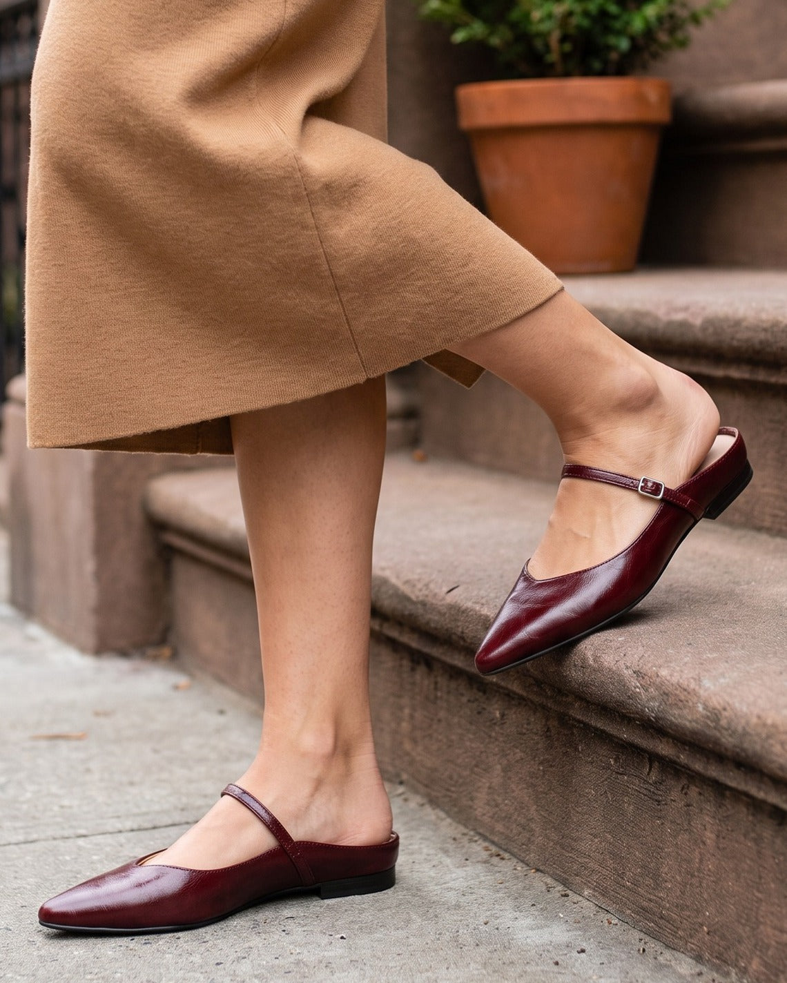 Verity wine-red mules worn with a camel skirt on brownstone steps